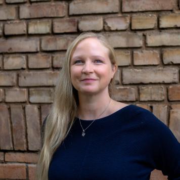 Portrait einer blonden Frau vor einer roten Backsteinwand